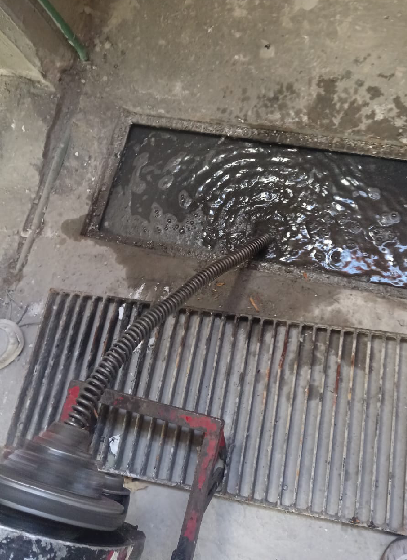 Maquina frente a un registro de drenaje inundado, destapacaños experts destapando